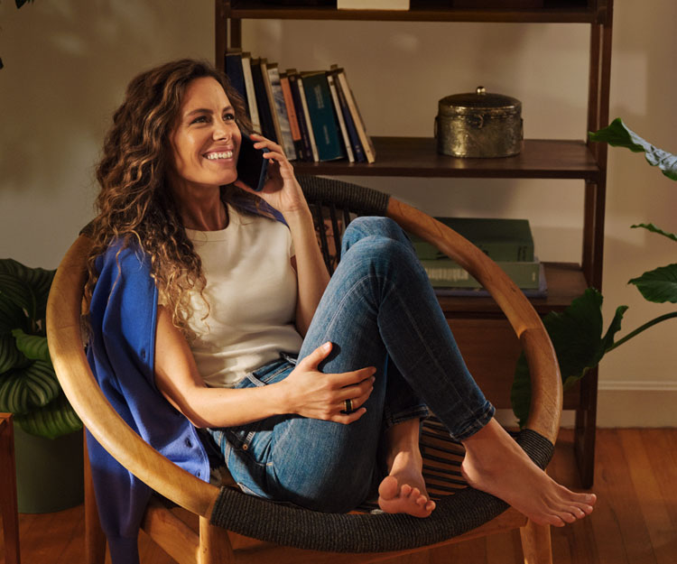 chica sonriendo, entada de forma relajada en una silla, hablando por teléfono